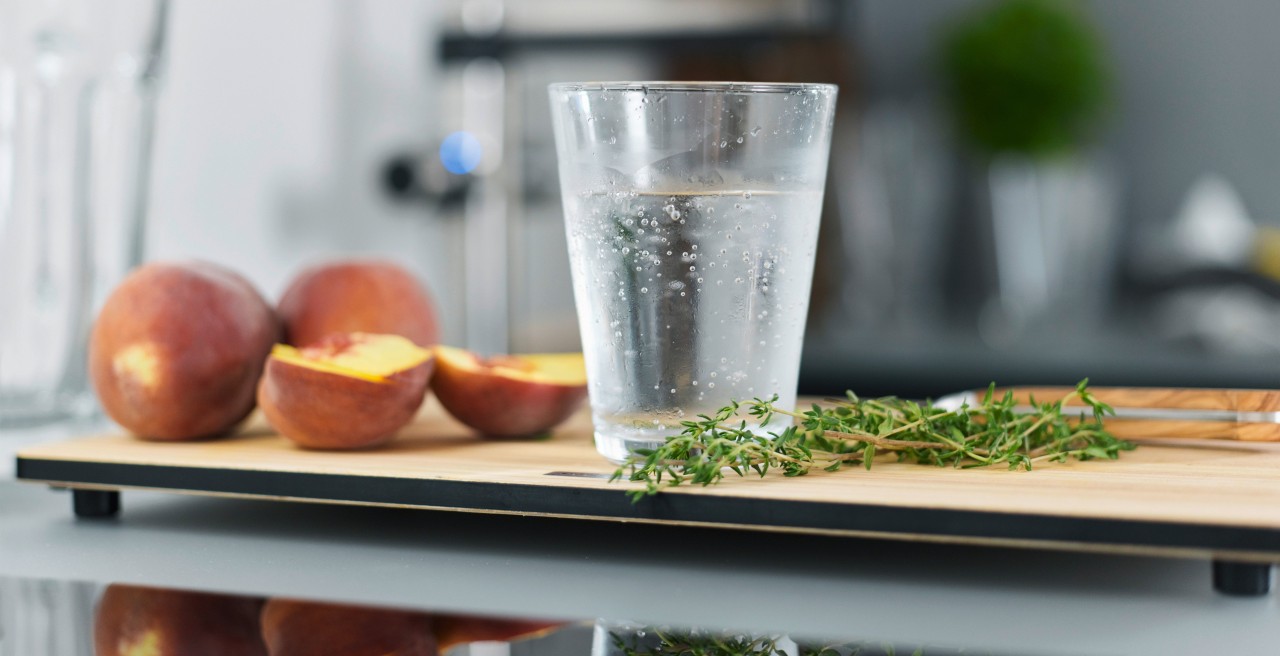 Geschnittene Pfirsische liegen neben einem Wasserglas