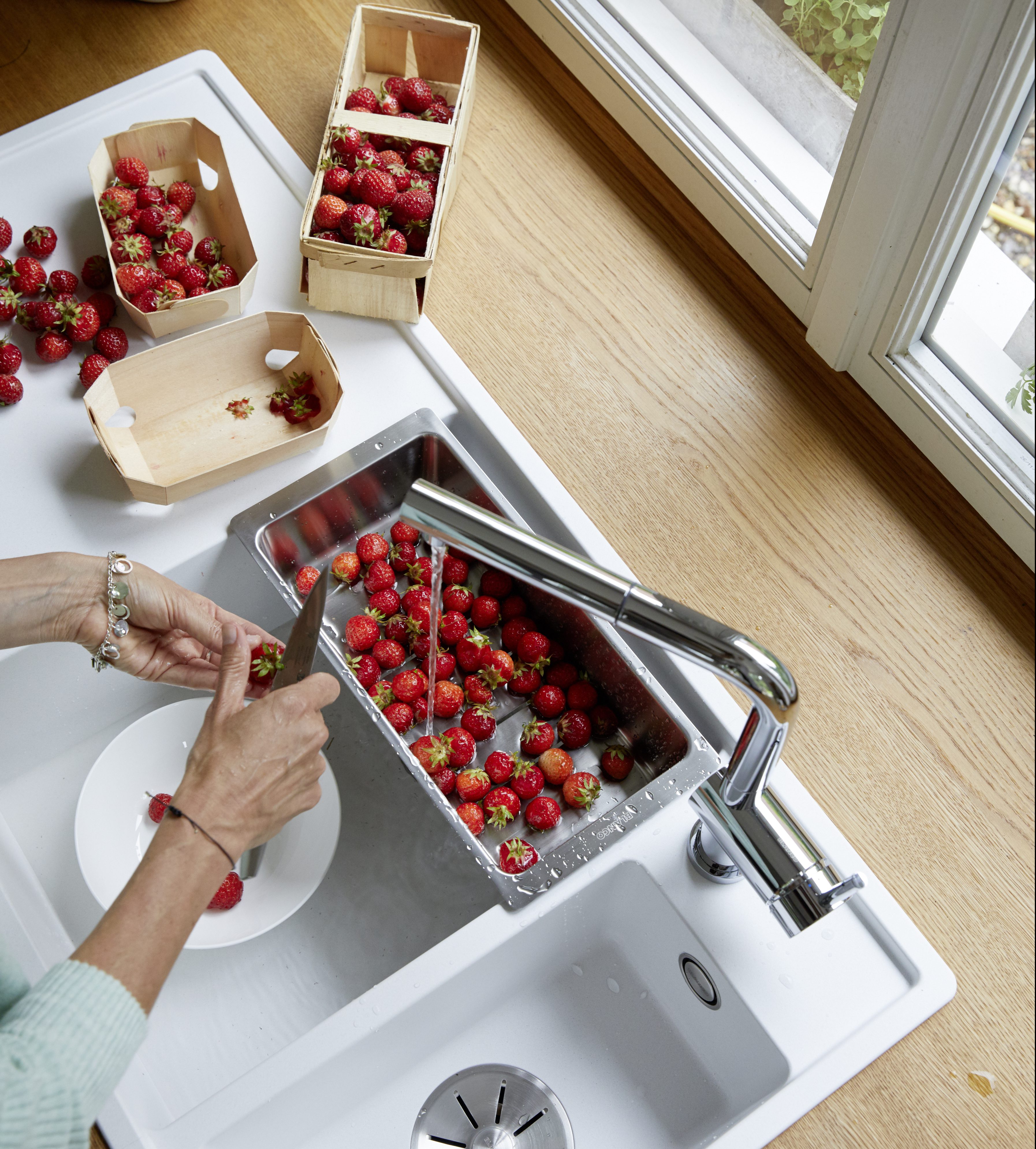 eine Frau schneidet Erdbeeren über einer BLANCO Spüle